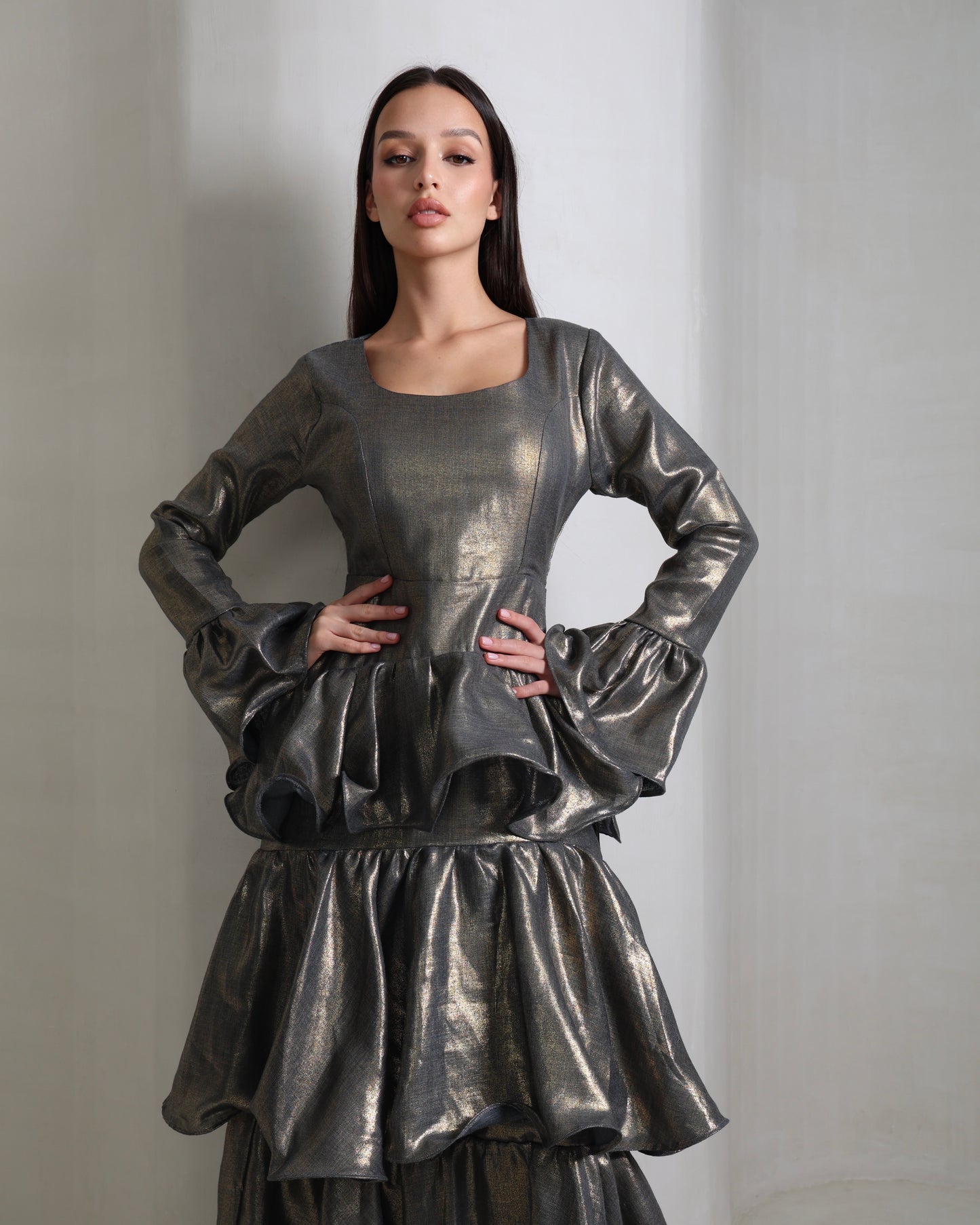 Woman wearing a metallic silver dress against a plain background